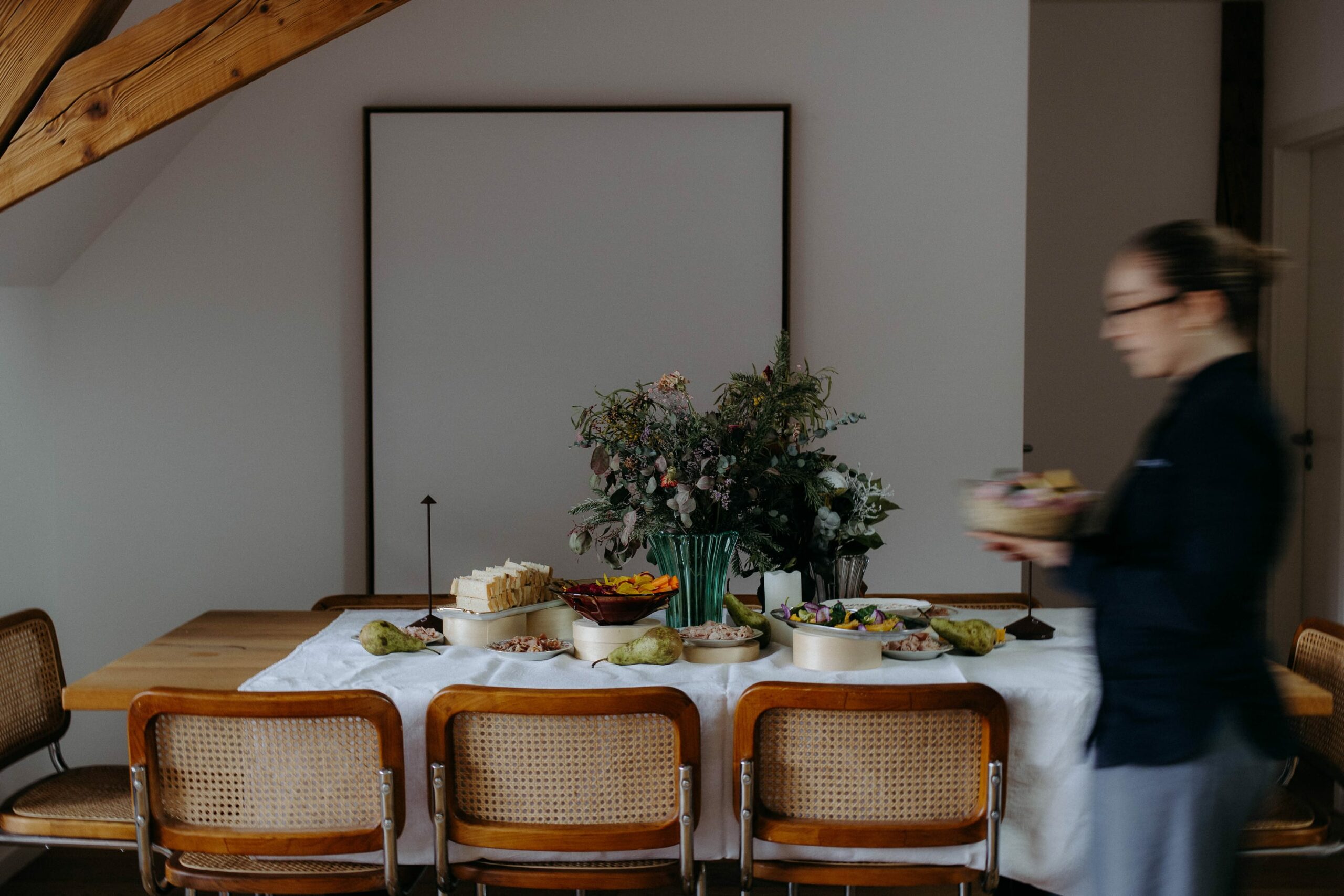 Cuisinière qui passe devant une table dressée, le rendant flou mais très artistique